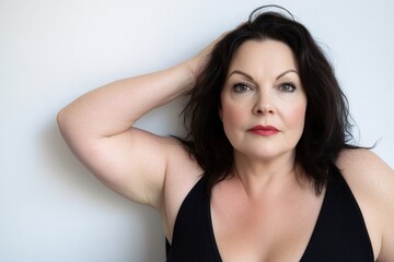 Fototapeta premium Confident Woman with Dark Hair Posing Elegantly Against a Light Background