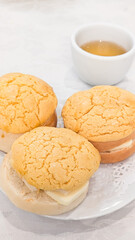 Photo of golden pineapple buns with a signature crackled top served on a plate, traditional Chinese cuisine and cultural celebration. Concept of Chinese new year, lunar year, dim sum, dessert