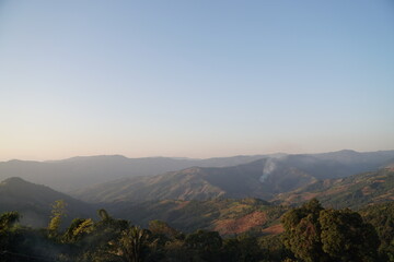 Naklejka premium Landscape of Morning Mist with Mountain Layer at north of Thailand. mountain ridge and clouds in rural jungle bush forest.