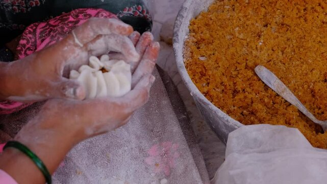 Woman making sweet rice modak stuffed with grated coconut and jaggery, Steamed or ukdiche Modak. It's a traditional sweet dish made out of coconut, jaggery