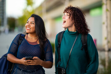 Two women smiling and walking outdoors with backpacks