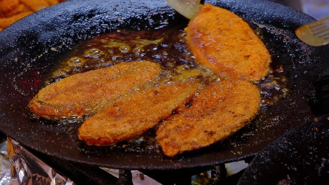 Fish fry on a frying pan with curry leaves. Close-up shot of Indian traditional Konkan style spicy fried fish.
