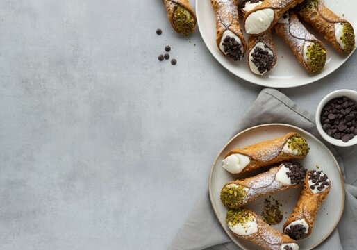 Typical sicilian cannoli filled with ricotta cream, chocolate chips and pistachios lying on plates, creating a delicious pastry composition