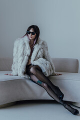 Attractive young caucasian woman wearing fur coat, black tights and sunglasses