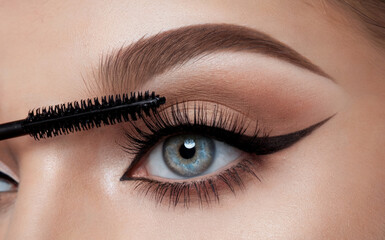 A close-up of a person's eye, emphasizing the eyelashes, eyeliner, and mascara applied. The eye is blue, and the eyelashes are long and voluminous. 