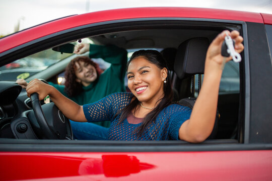 Two women celebrating with car keys in red car