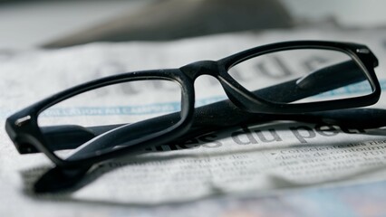 A close up of the glasses on the newspaper.