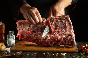 Expert hands prepare a large cut of meat on a wooden board in a rustic kitchen setting. Asian cuisine