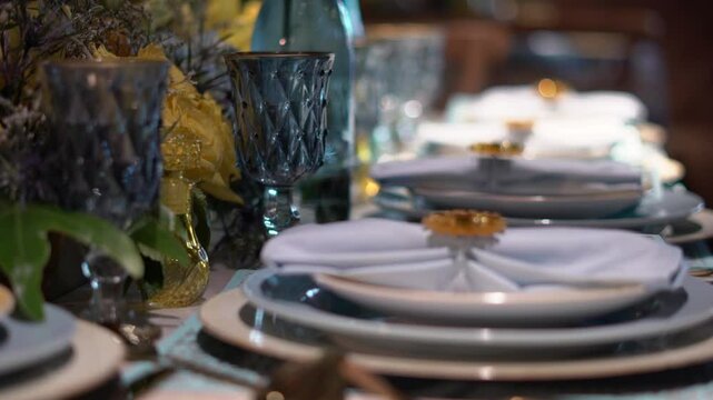 person placing a napkin on a plate at a decorated wedding table