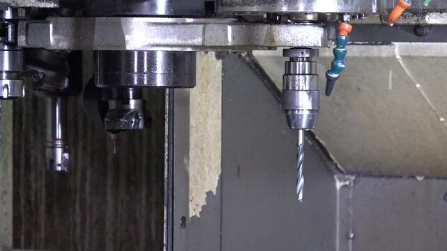 Close up view of automatic cnc drill or lathe machine changing drilling bit process in a factory.