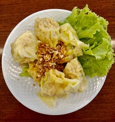 Boiled Pork Dumplings in white plate on serv on the wooden table