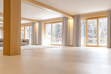 Obraz premium Spacious living area with large windows overlooking a snowy forest in winter