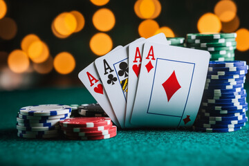 winning poker hand of four aces displayed on a green casino table, surrounded by colorful poker chips. Warm, blurred bokeh lights create a vibrant casino atmosphere in the background, cheating 