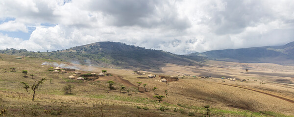 Naklejka premium Scenic view of traditional Masai village surrounded by mountains in Serengeti Tanzania East Africa