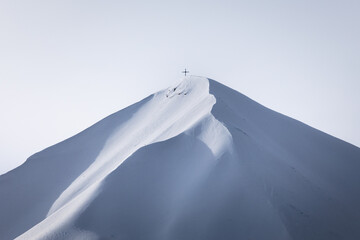 shadows of the mountain covered by snow; mountain peak with a cross at the top; beautiful shapes of...
