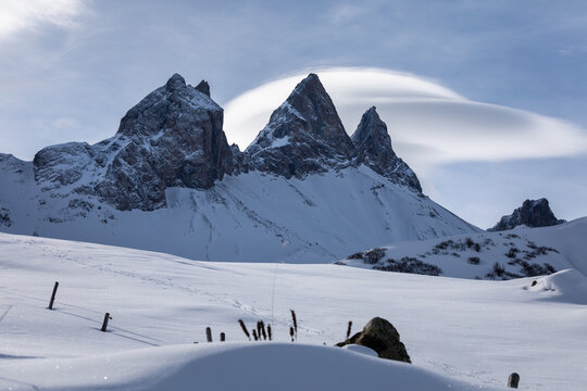 Aiguilles d'Arves mountains covered by snow in winter; sunny day in the french alps; lenticular cloud over the mountains