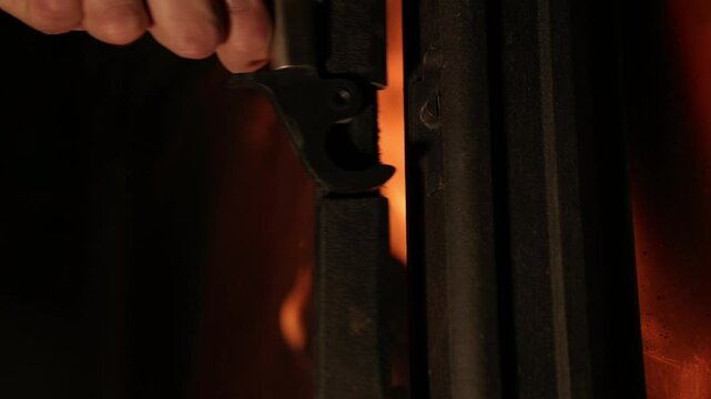 Opening the fireplace door handle. Adding logs to the firebox