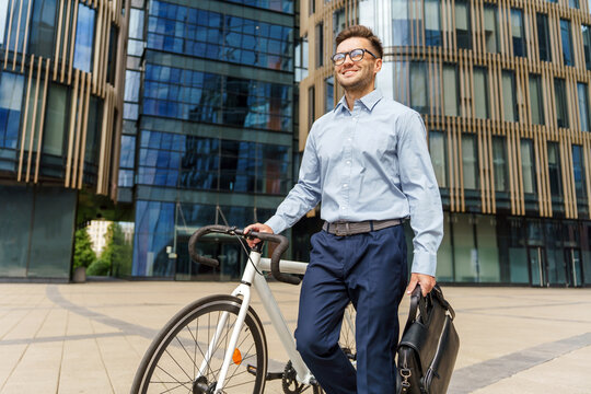 Business professional rides bicycle to work in modern city setting while carrying a briefcase