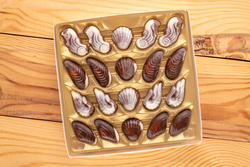 How many chocolate candies with ceramic and wooden utensils on a wooden table, close-up, top view.