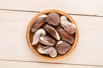 How many chocolate candies with ceramic and wooden utensils on a wooden table, close-up, top view.