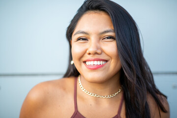 Smiling woman with long dark hair wearing a gold chain necklace