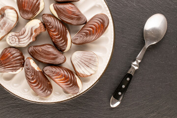 Several chocolate candies with ceramic dishes on slate stone, close-up, top view.