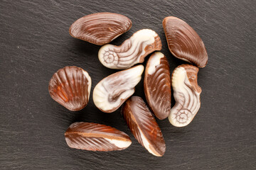 Several chocolate candies with ceramic dishes on slate stone, close-up, top view.