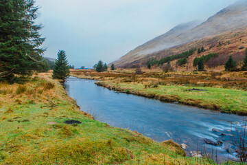 Kinglas Water river with fog and mountains in the background during Scottish Winter - captured from the Butter Bridge in Glen Kinglas, Scotland. 