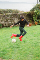 Fototapeta premium A young boy in black jumper practices his rainbow kick as he improves his football skills