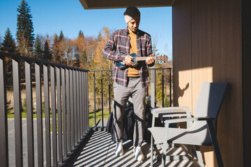 young musician stands on a sunlit balcony, playing the ukulele while gazing into the distance....