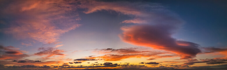 A vibrant sunset or sunrise sky panorama with cloudscape in soft magenta, pink and orange tones as a background or texture