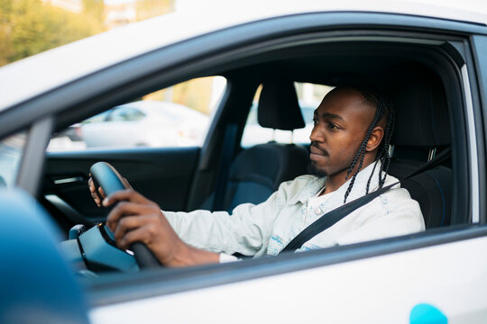 Young delivery man driving a car carefully through the city