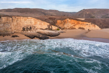 Aerial view of beautiful sandy beach and cliffs of Pacific Ocean coast on Highway 1 in California,...