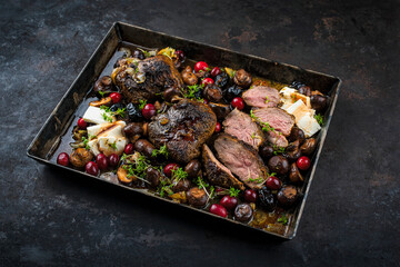 Traditional Greek braised lamb steaks with feta cheese, mushrooms and cranberries in a hearty meat sauce with red wine served as close-up in a rustic metal tray