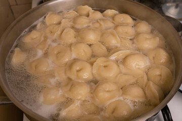 The meat dumplings are cooked in a pot of boiling water.
