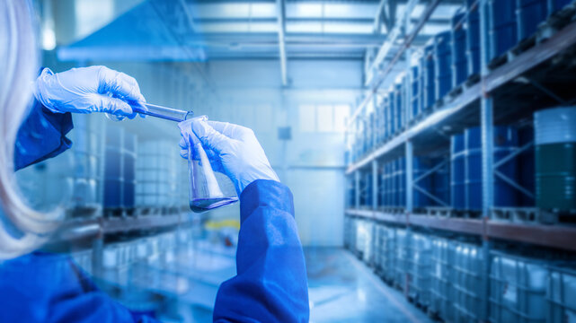 Woman laboratory technician at oil refinery. Checking fuel for quality. Inspector hands with flasks near warehouse. Control petroleum products for presence of impurities. Petroleum environmental test