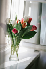 Tender bright tulips close up in the vase on the window in the spring morning. Springtime at home