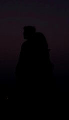 Silhouettes of young Asian couple Emotional connection Turn your back so you can't see your face with the background scene is the sea.