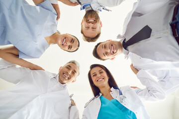 Group portrait of happy doctors and nurses standing in a circle in the hospital. Showcasing...