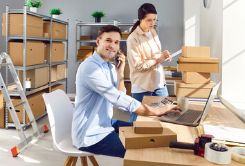 Work at E commerce business warehouse. Male manager at table in goods storage room calls client,...