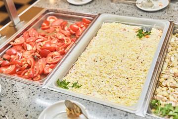 Fresh sliced tomatoes and mimosa salad, traditional dishes in metal containers, a buffet with Russian dishes. With space to copy. High quality photo