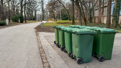 Row of green recycling bins in a park highlighting environmental sustainability and waste...