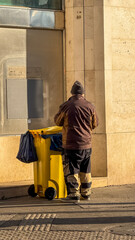 A street cleaner, likely aimed at European urban maintenance, manages a yellow bin, highlighting...