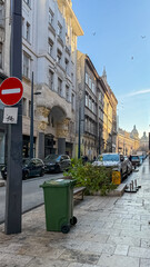 Obraz premium A European urban street showcases post-Christmas cleanup with discarded trees and trash bins, reflecting waste management during the holiday season