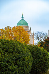 A historic building with a green dome, surrounded by colorful autumn leaves and clear skies, in a calm, picturesque atmosphere.