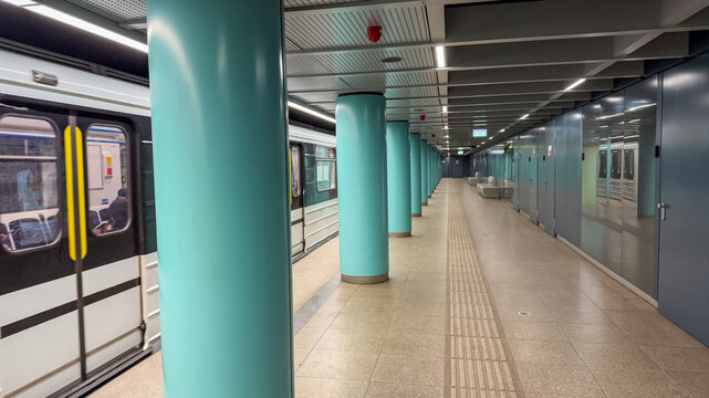 Empty subway station platform with turquoise pillars in urban setting, representing urban transportation and the concept of solitude