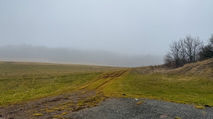 Foggy landscape with a dirt path in a rural field, symbolizing solitude and introspection during late autumn