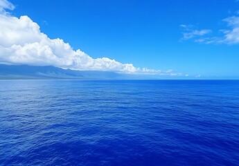 Obraz premium Serene Ocean Landscape: Blue Water, Mountains, and Clouds