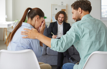 Obraz premium In a therapy session, a husband provides solace to crying, sad wife, guided by by the psychologist. Family showing power of emotional connection as the couple navigates challenges together.