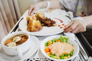 Female patient hands ready to eat a tray full of healthy dietary vegan food served in hospital